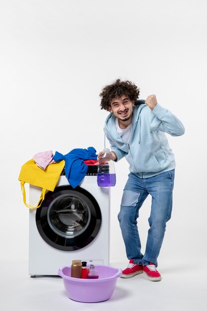 Vista frontale del giovane maschio con la rondella che tiene la polvere liquida sulla parete bianca