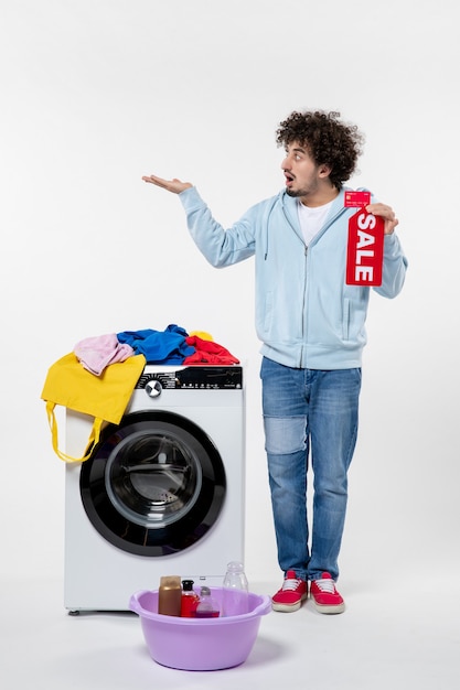 Front view of young male with washer holding red sale banner on a white wall