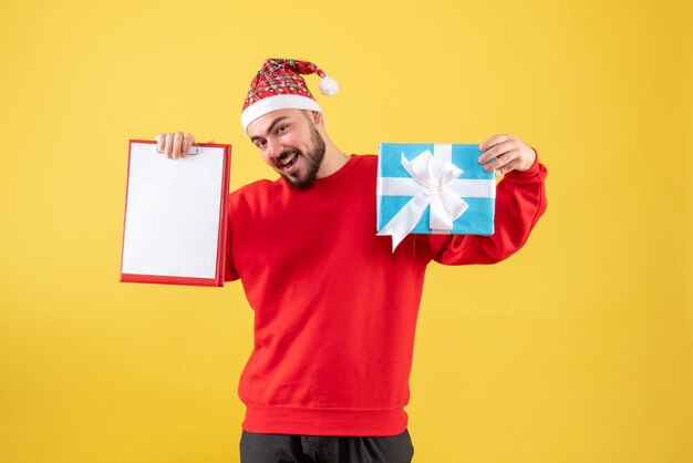 Front view young male with xmas present and note on yellow background