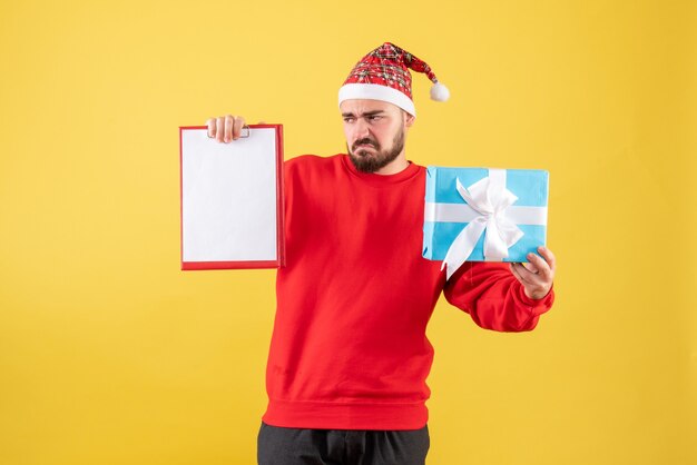 Вид спереди молодой самец с подарком на рождество и запиской на желтом фоне
