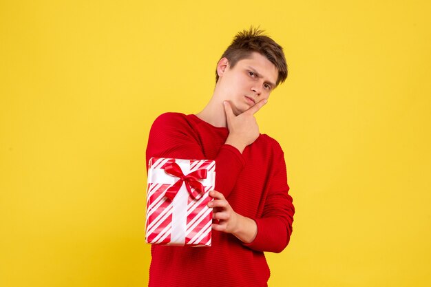 Front view young male with xmas present on yellow background