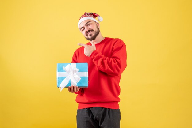 Front view young male with xmas present on yellow background