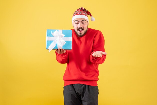 Front view young male with xmas present on yellow background