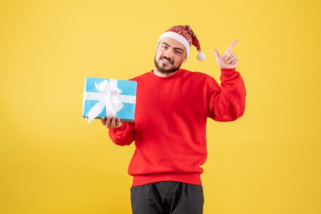 Front view young male with xmas present on yellow background