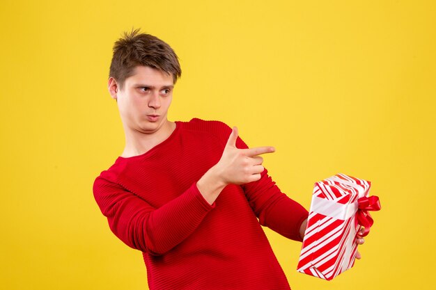 Front view young male with xmas present on yellow desk