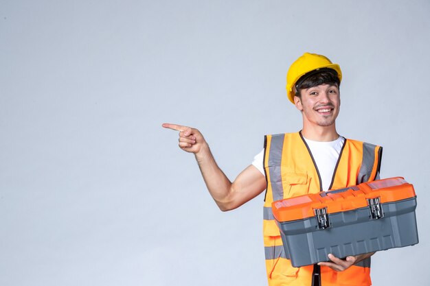 front view young male worker holding heavy tool case on white background