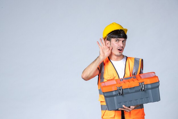 front view young male worker holding heavy tool case on white background