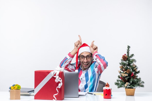 Front view young male worker sitting in his working place excited on white background