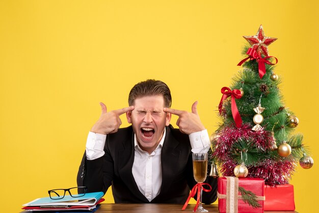 Front view young male worker sitting with xmas presents and tree