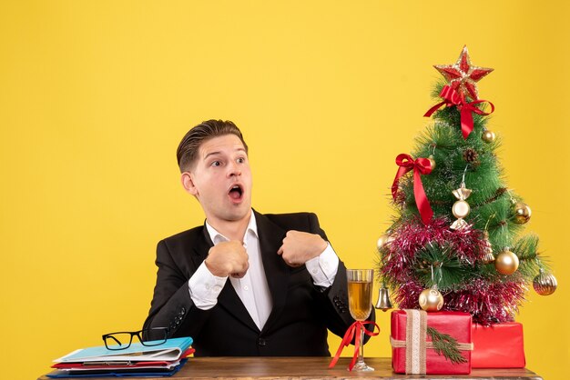 Front view young male worker sitting with xmas presents and tree