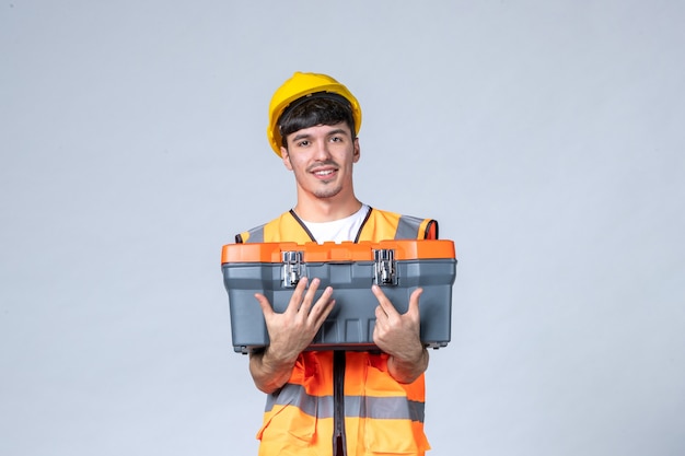 Front view young male worker with tool case on white background