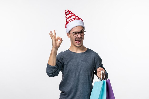 Front view of young man after holiday shopping on white wall