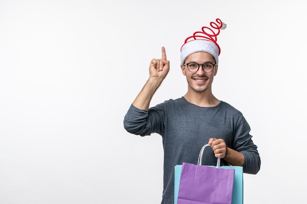 Front view of young man after holiday shopping on white wall