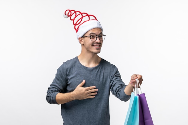 Front view of young man after holiday shopping on white wall