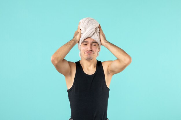 front view of young man after shower on blue wall