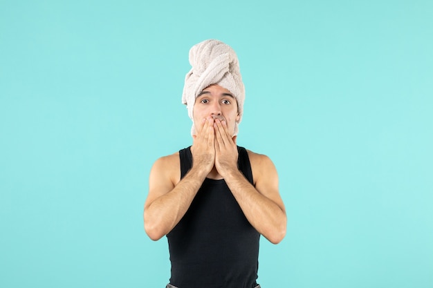 front view of young man after shower on blue wall