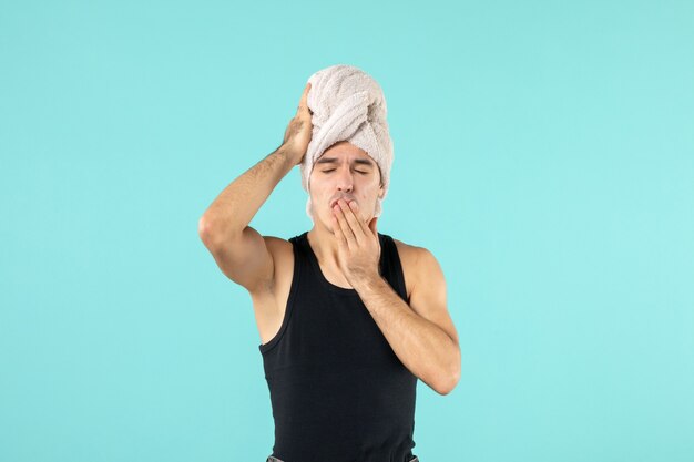 front view of young man after shower on blue wall