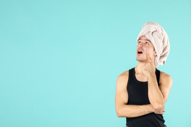 front view of young man after shower on blue wall