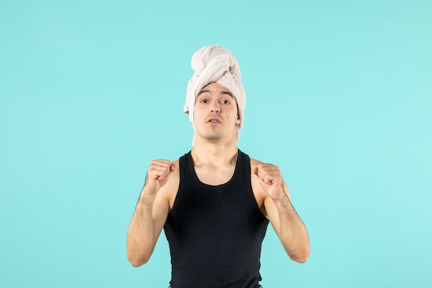 front view of young man after shower on blue wall