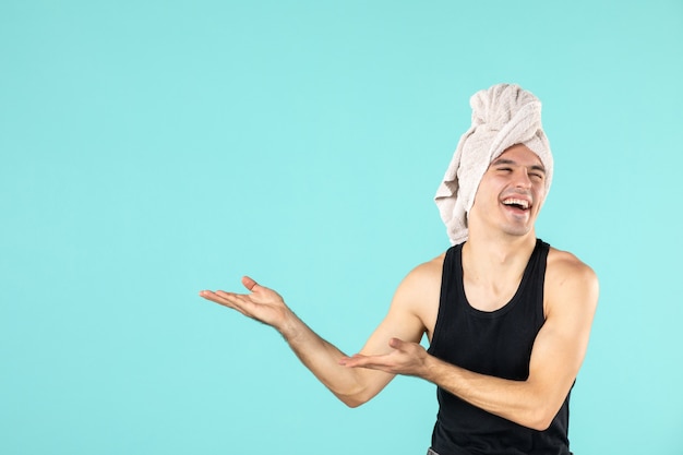 front view of young man after shower on blue wall