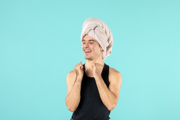 파란 벽에 웃고 있는 샤워 후 젊은 남자의 전면 모습