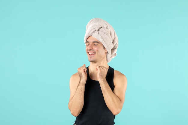 front view of young man after shower smiling on a blue wall