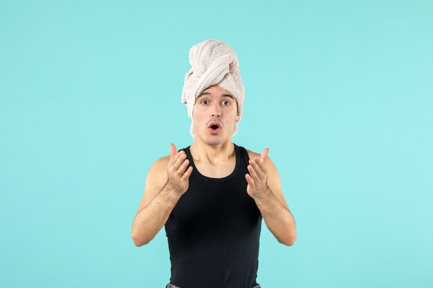 front view of young man after shower surprised on blue wall