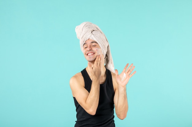 Free photo front view of young man after shower with cream on his face on blue wall