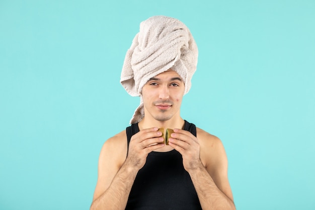 Free photo front view of young man after shower with kiwi slices on blue wall