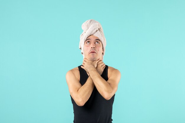 вид спереди молодого человека после душа с полотенцем на голове, который подавился синей стеной