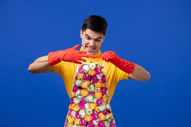 Free photo front view of young man in apron taking off his gloves on blue wall