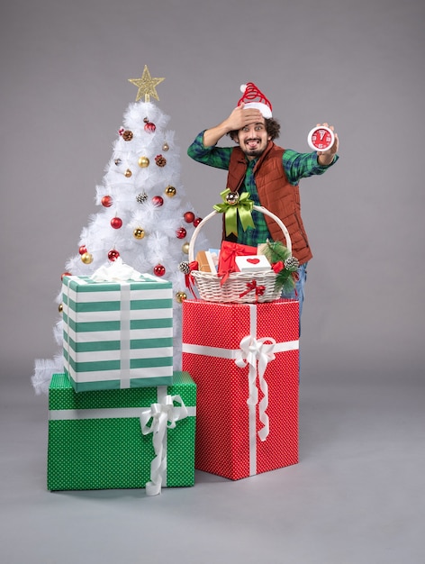 Front view young man around holiday presents on a grey 