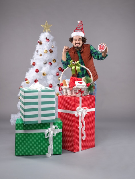 Front view young man around holiday presents on grey