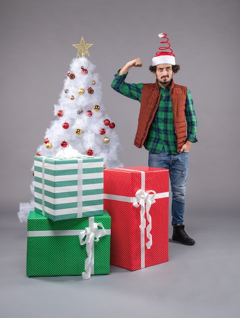 Front view young man around presents on grey floor xmas new year gift