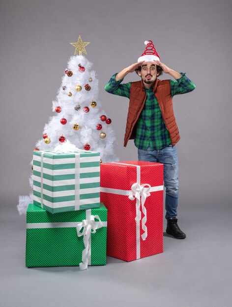 Front view young man around presents on grey 