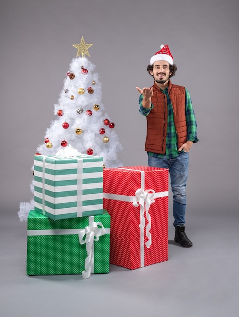 Front view young man around presents on the grey