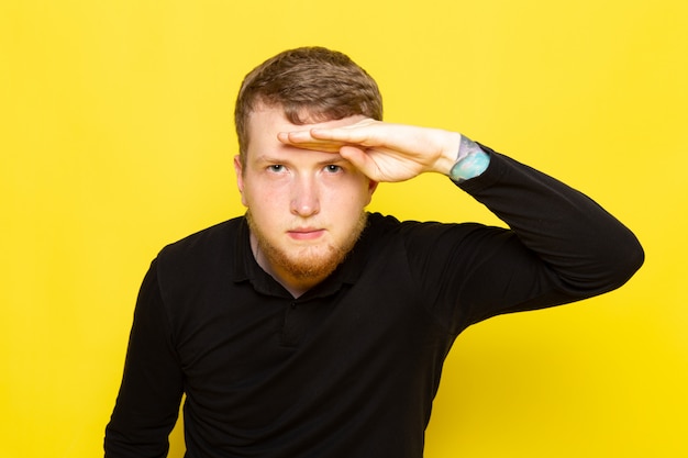 Front view of young man in black shirt posing looking into the distance