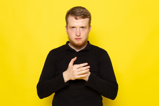 Front view of young man in black shirt posing with aggressive gesture