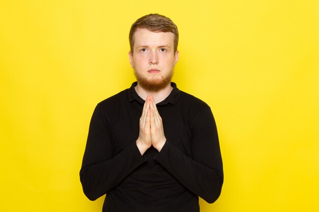 Front view of young man in black shirt posing with begging gesture