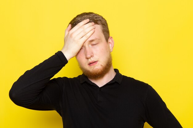 Front view of young man in black shirt posing with dissapointed expression