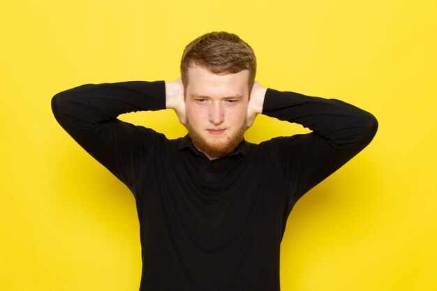 Front view of young man in black shirt posing with shut ears