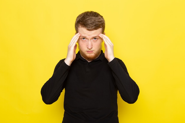 Front view of young man in black shirt posing with stressed expression