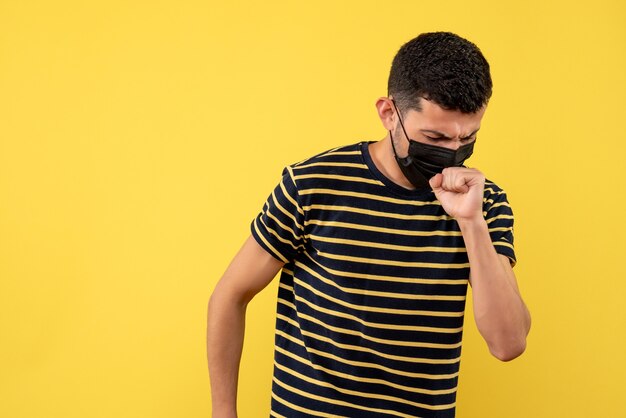 Front view young man in black and white striped t-shirt coughing on yellow background