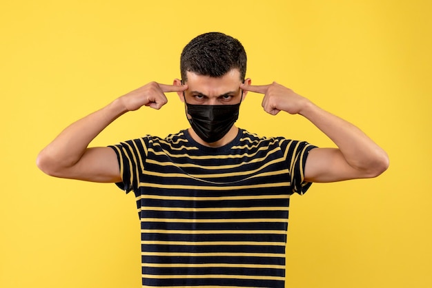 Free photo front view young man in black and white striped t-shirt putting fingers on his temple on yellow background