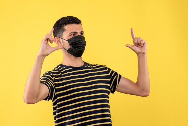 Front view young man in black and white striped t-shirt showing size on yellow background