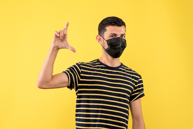 Front view young man in black and white striped t-shirt standing on yellow background