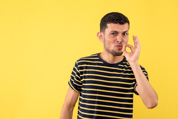 Front view young man in black and white striped t-shirt standing on yellow isolated background