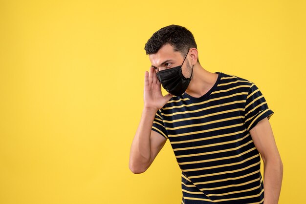 Front view young man in black and white striped t-shirt yellow background copy space