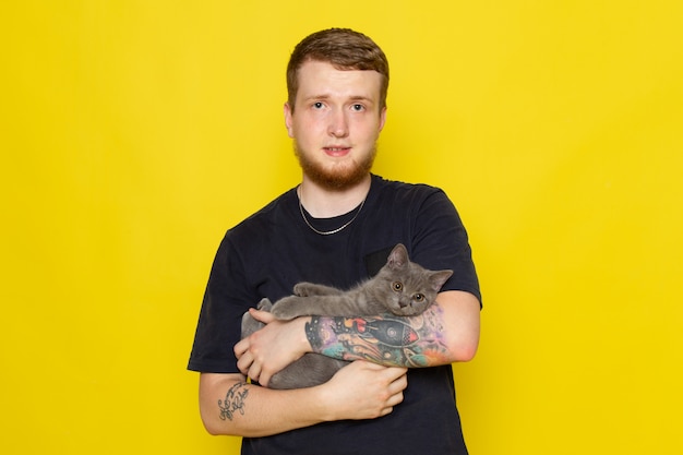 Вид спереди молодого человека в синей рубашке держит милый серый котенок
