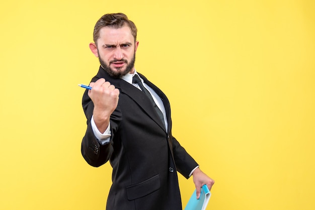 Front view of young man businessman implying power on yellow